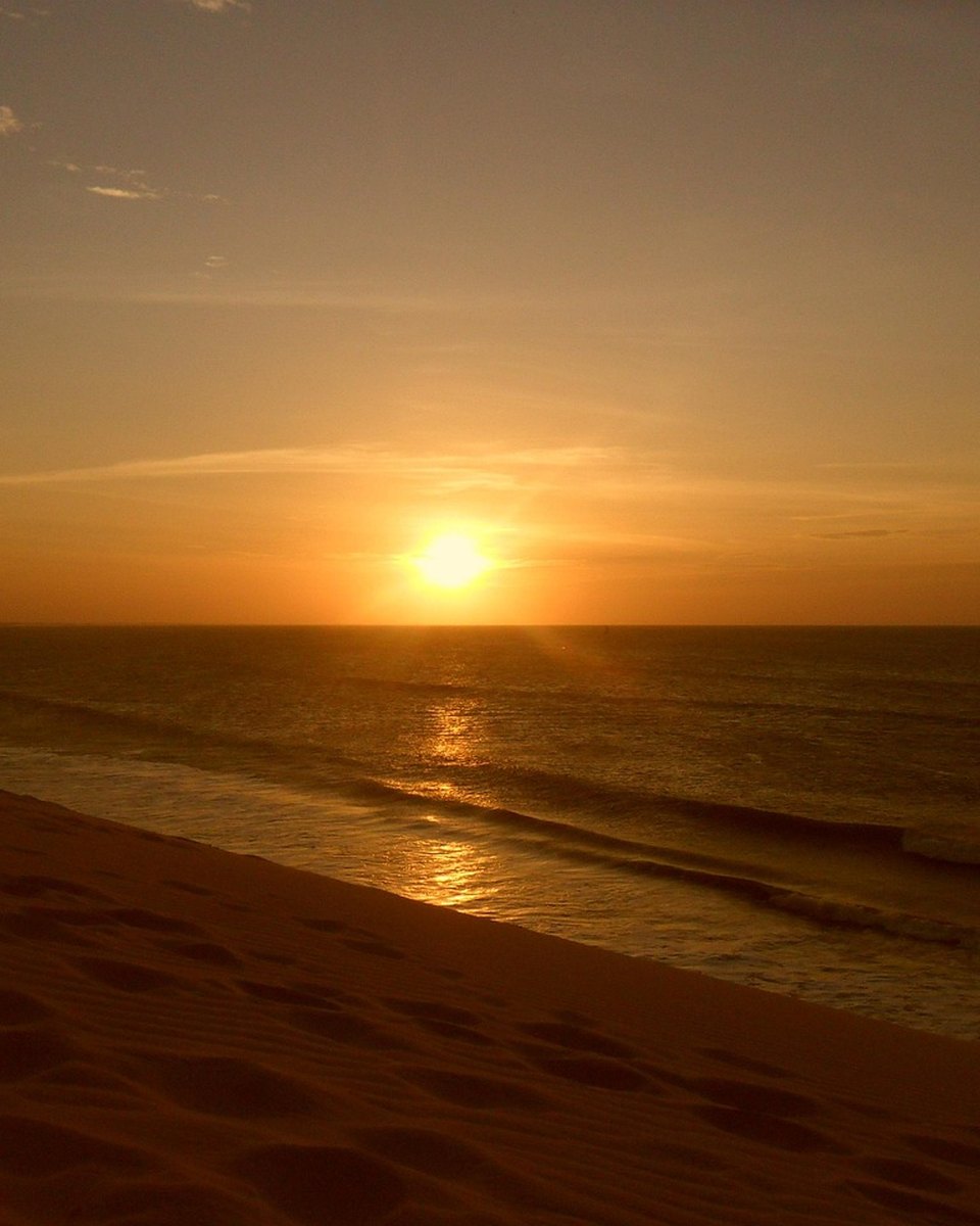 Pôr do sol dourado sobre o mar na Rota das Emoções