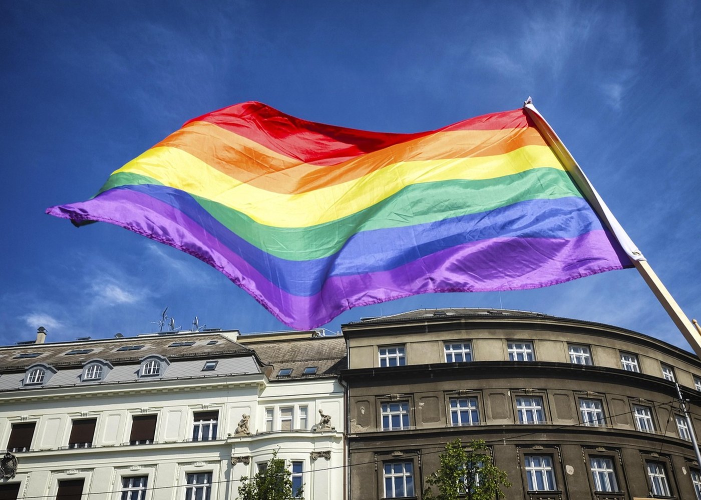 Bandeira do orgulho LGBTQIA+ ao vento sob o céu azul